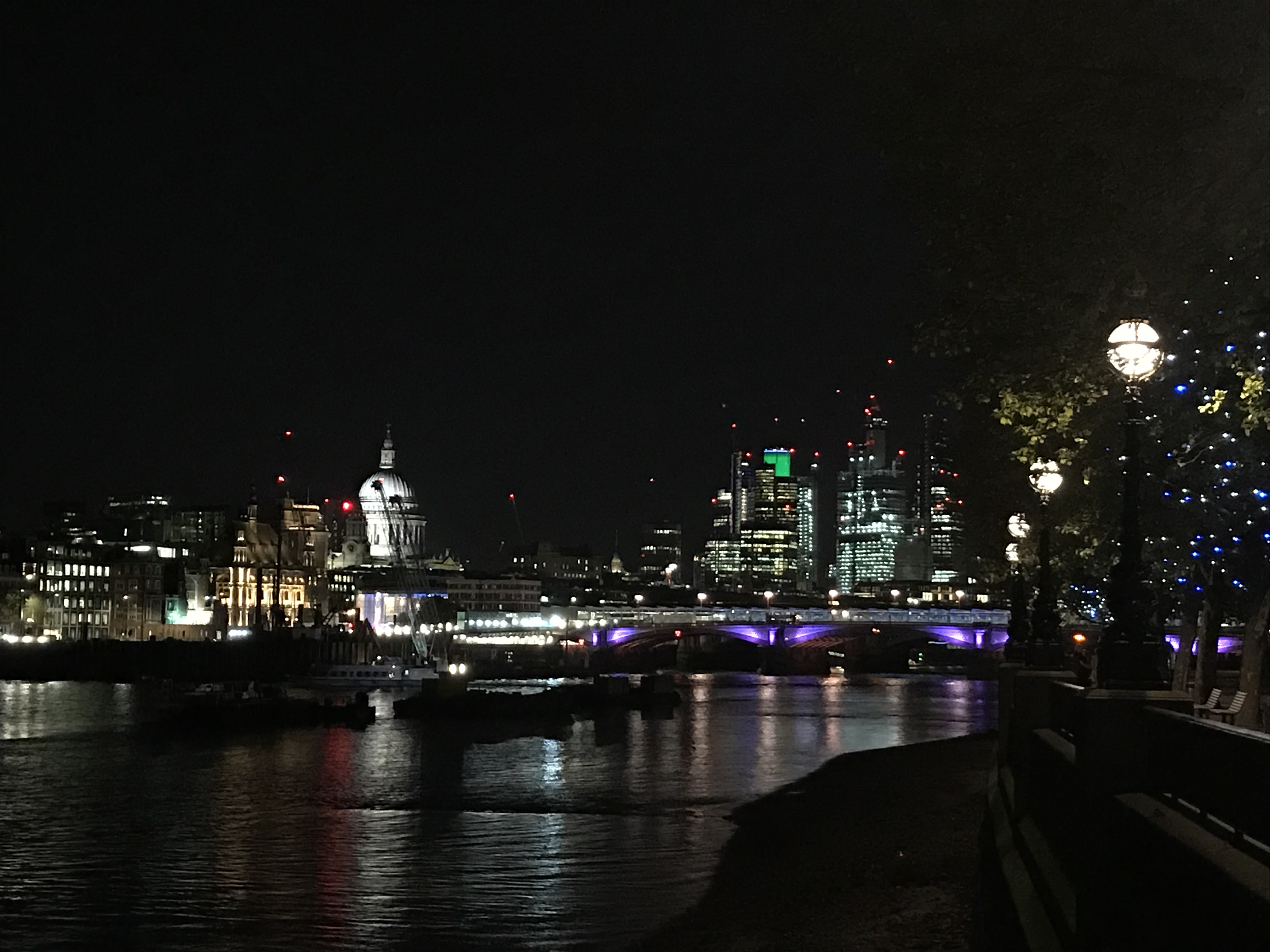 Londons Skyline bei Nacht vom Ufer der Themse aus